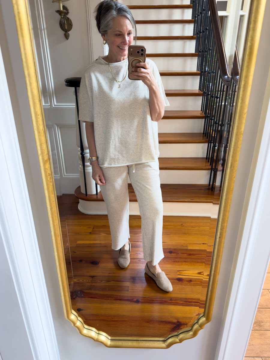 Woman wearing a cream knit lounge set with neutral mules in mirror selfie