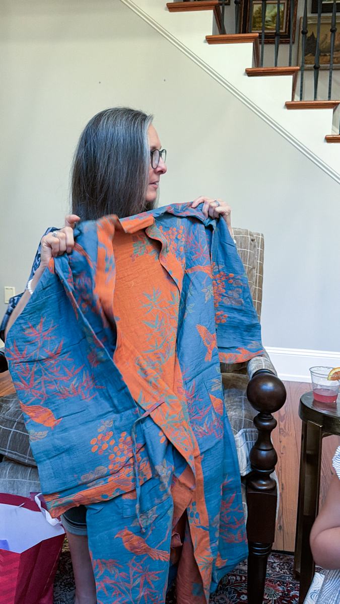 Woman holding a blue and orange bird print kimono during gift opening