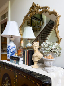 Summer to fall console table with blue and white lamp, vintage books, classical bust, hydrangeas, candles, and collected decor.