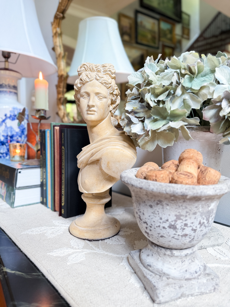 Classical bust with muted hydrangeas, vintage books, stone urn, and blue and white lamp for transitional fall decorating.