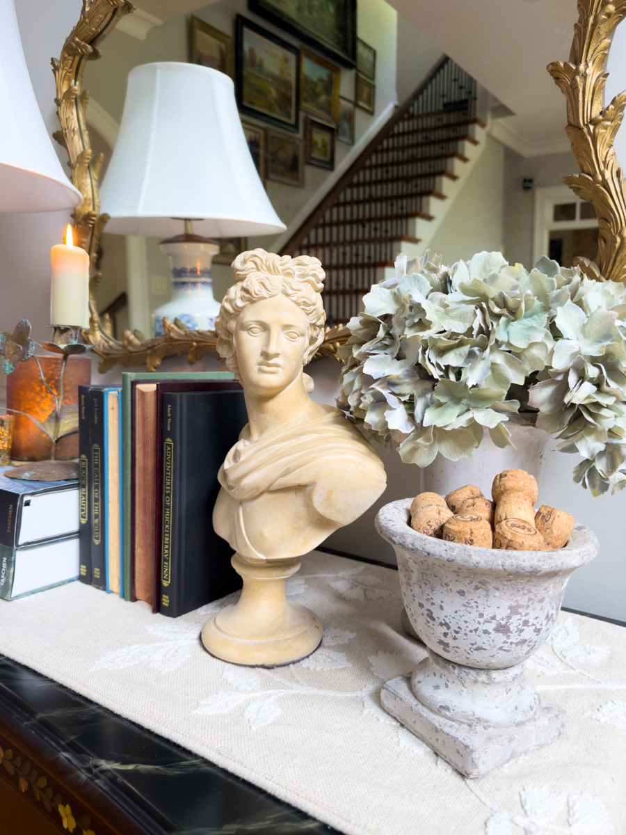 Classical bust, faded hydrangeas, vintage books, and weathered stone urn styled for simple early fall decorating.