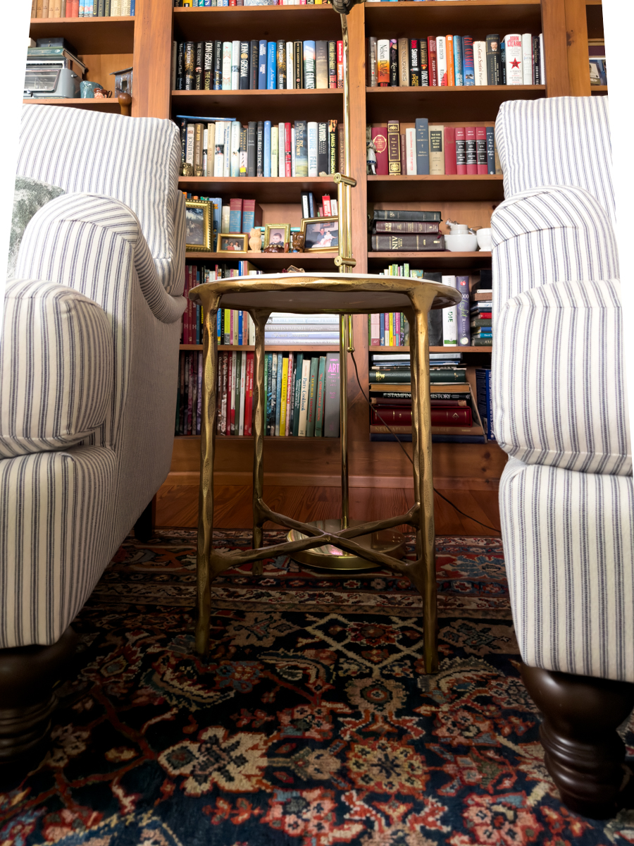 Brass side table with marble top positioned between two striped upholstered chairs