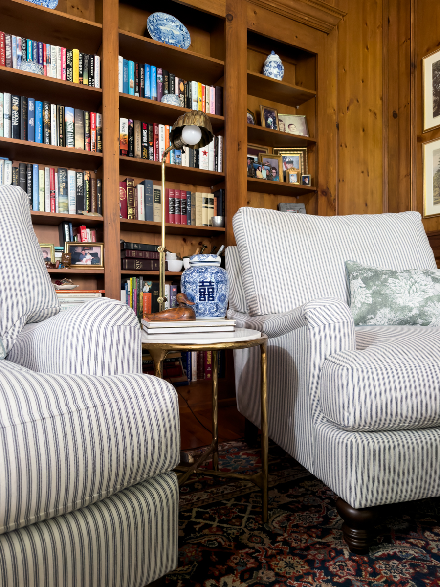 Two blue and white striped reading chairs with a marble and brass table between them