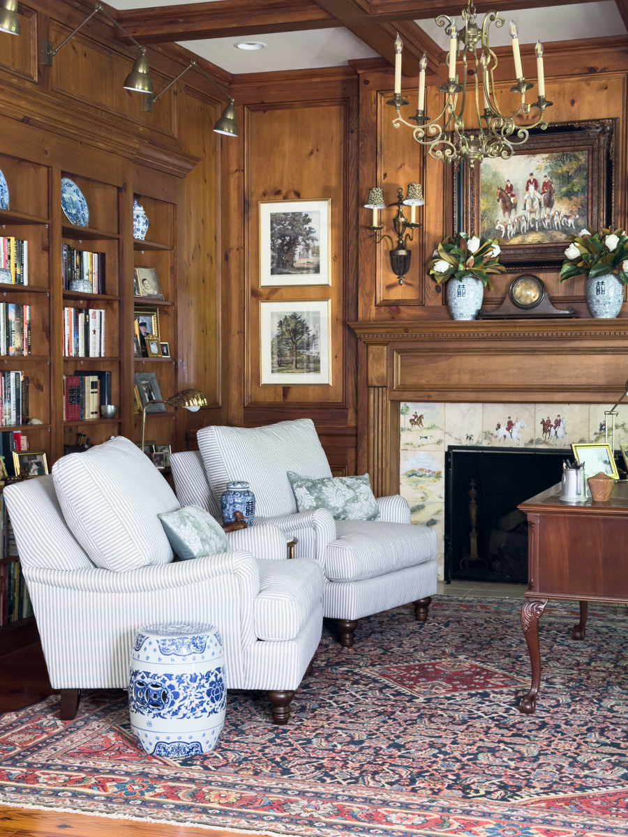 Traditional den with fireplace, striped reading chairs, built-in bookcases, and Persian-style rug