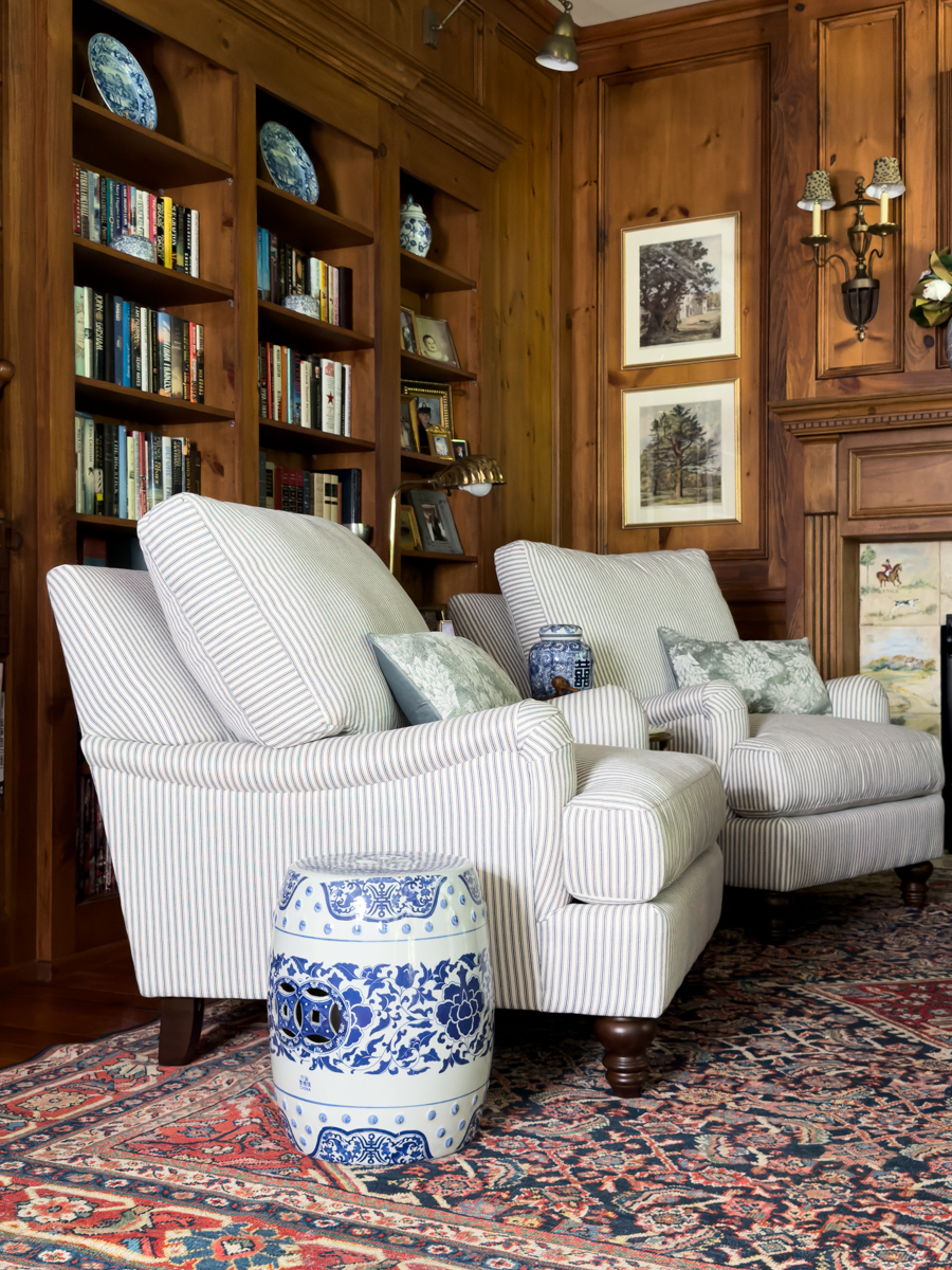 Light striped chairs and blue and white garden stool in a cozy wood-paneled den