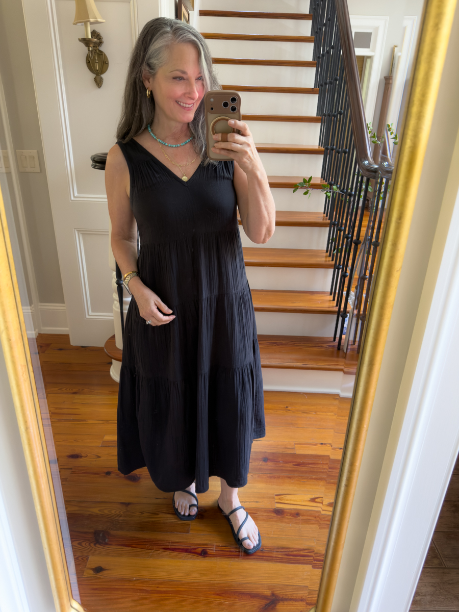 Woman over 50 wearing a black gauze sleeveless maxi dress with sandals for effortless summer style
