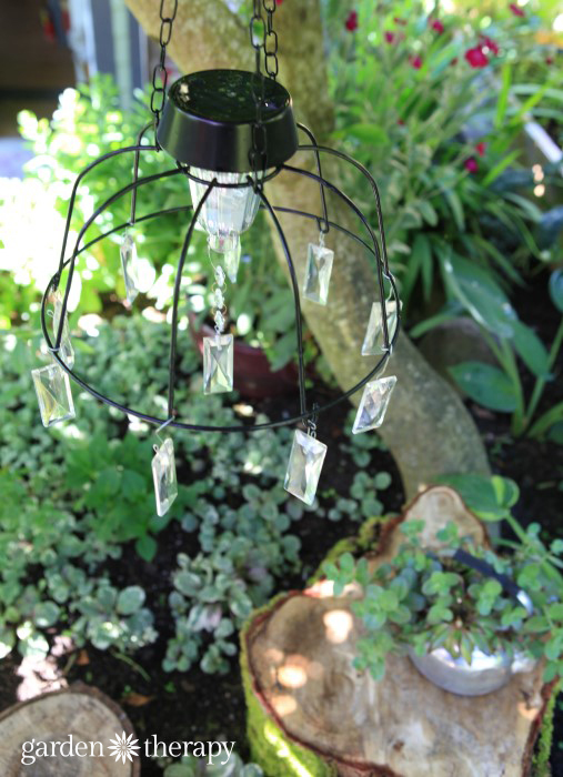 DIY Solar Light Chandelier hanging over rustic tree stump table and chairs