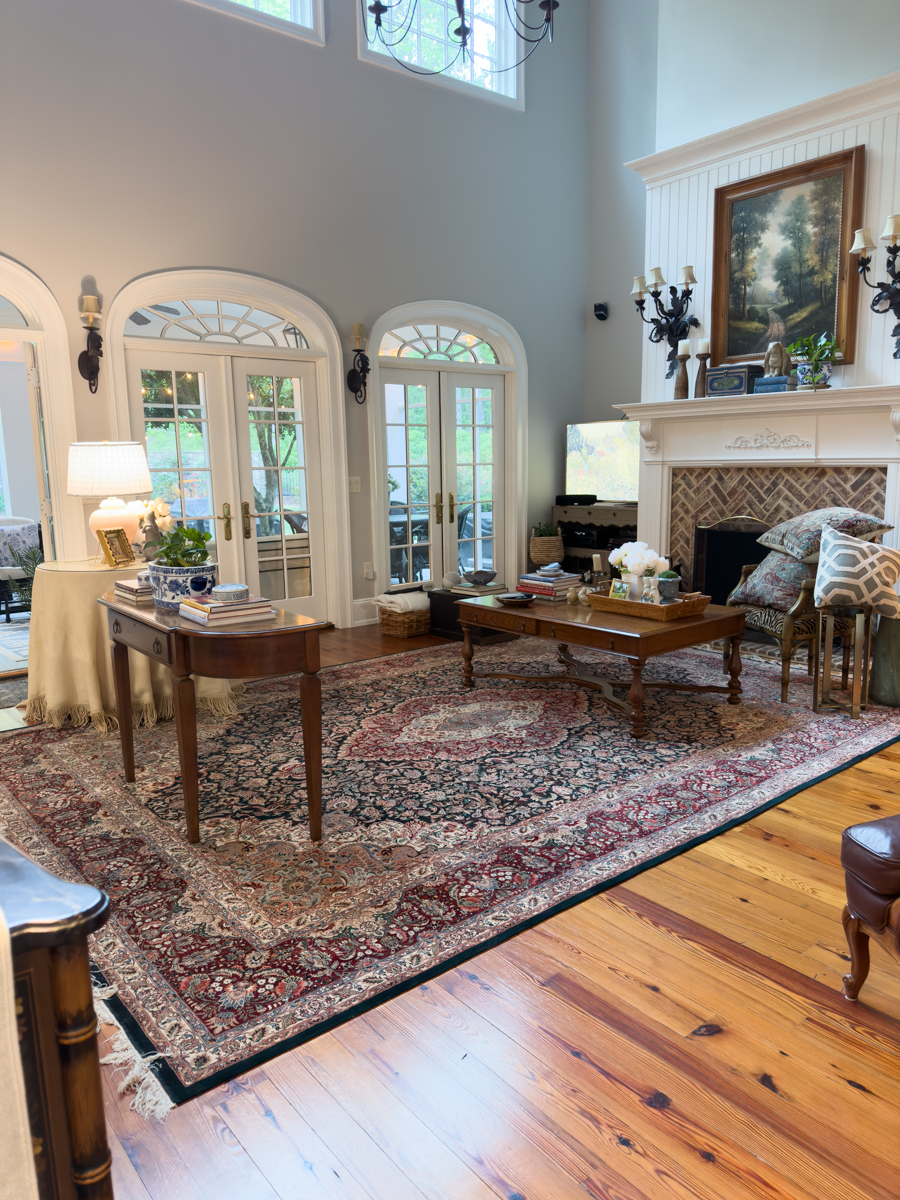 Traditional living room with large vintage style rug, fireplace, French doors, and collected furniture