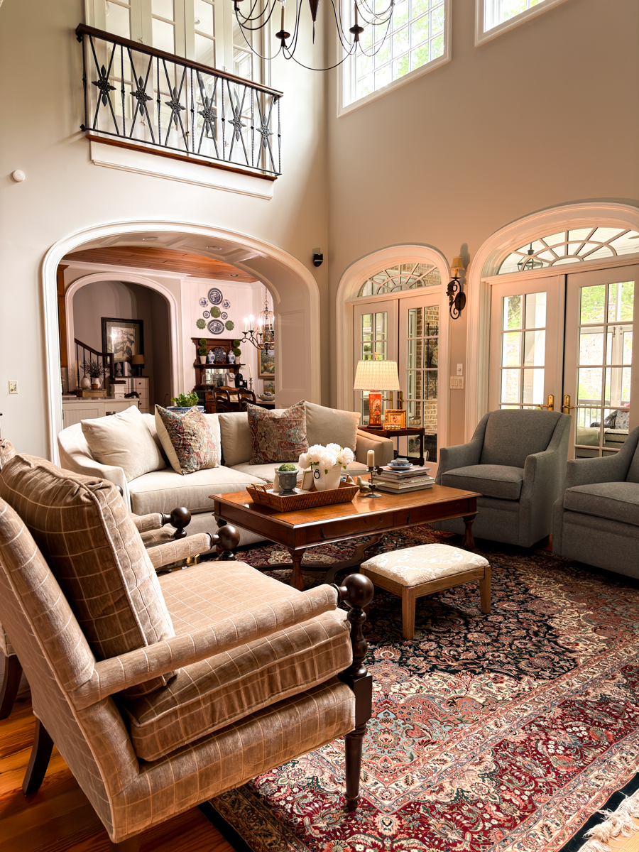 Traditional living room with patterned rug, classic chairs, sofa, fireplace, and collected decor