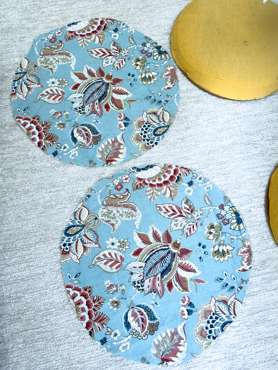 Two round pieces of blue floral upholstery fabric cut to recover rattan chair seats.