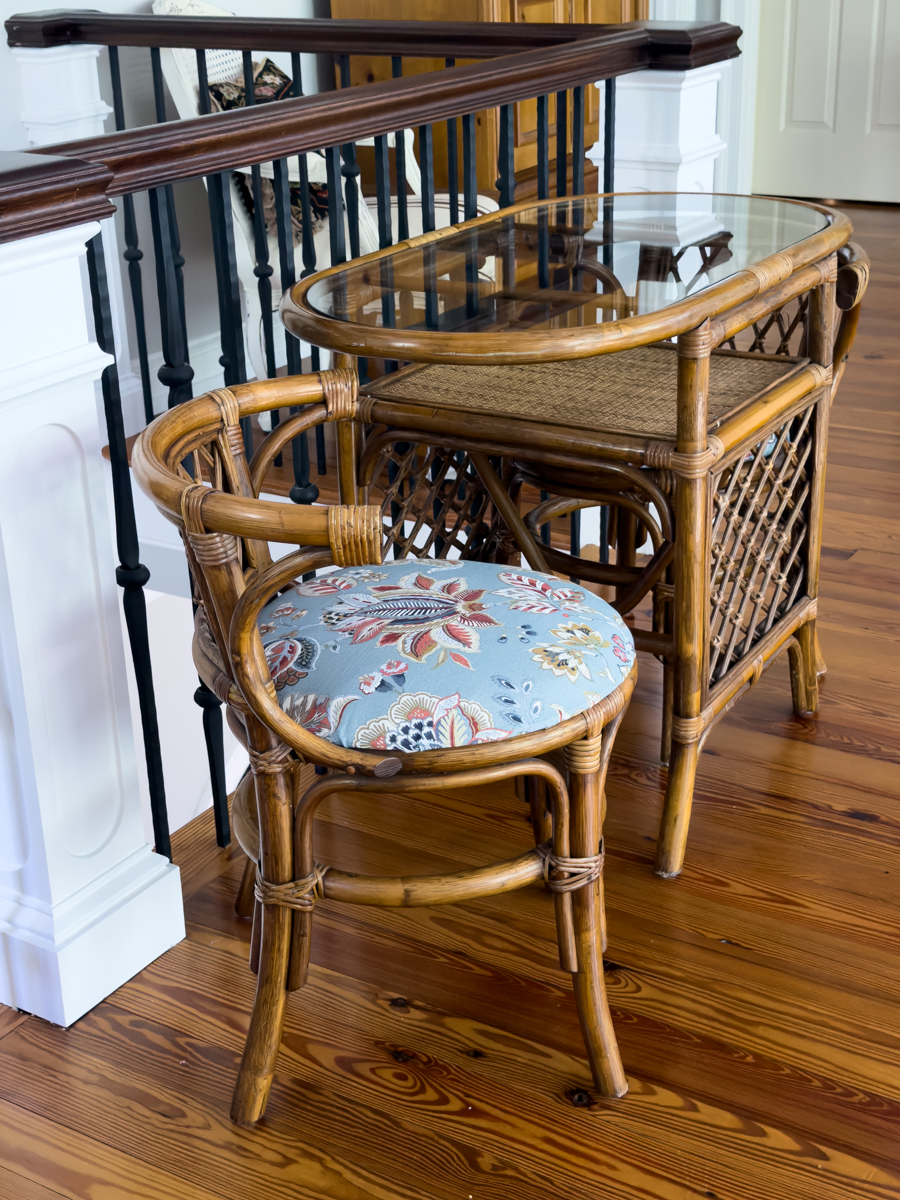 Rattan chair with a newly recovered round seat in blue floral patterned fabric.