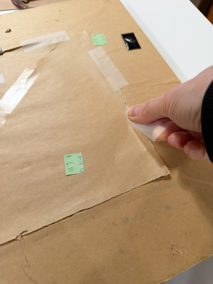 Taping brown paper backing closed on thrifted picture frame