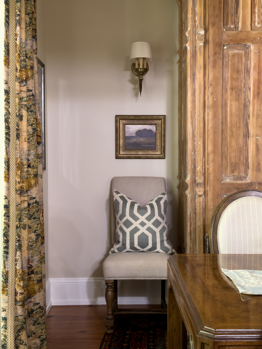 Dining room corner styled with vintage gold wall art and upholstered chair