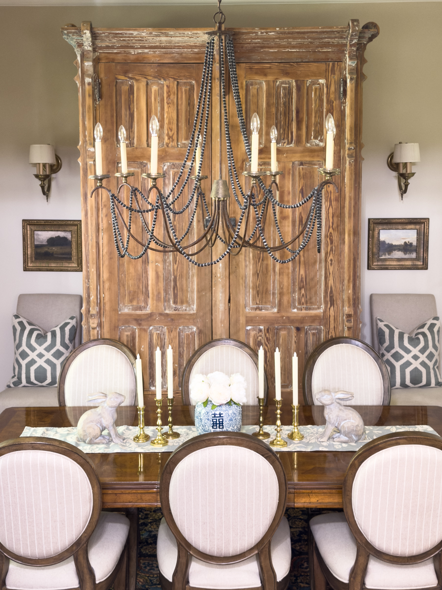 Antique wood cabinet styled in a traditional dining room with upholstered chairs and collected decor