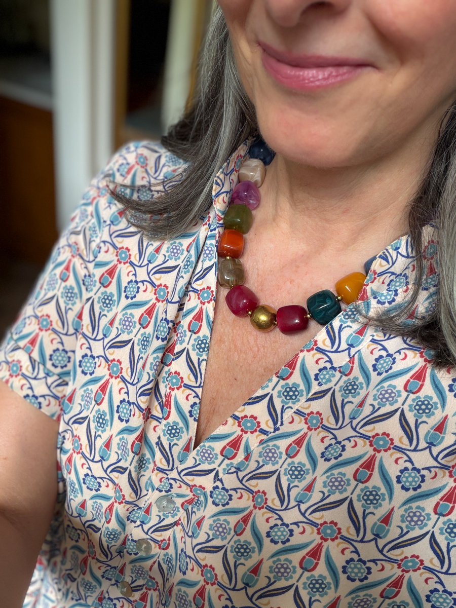 Close-up of colorful statement necklace styled with a blue and coral printed dress