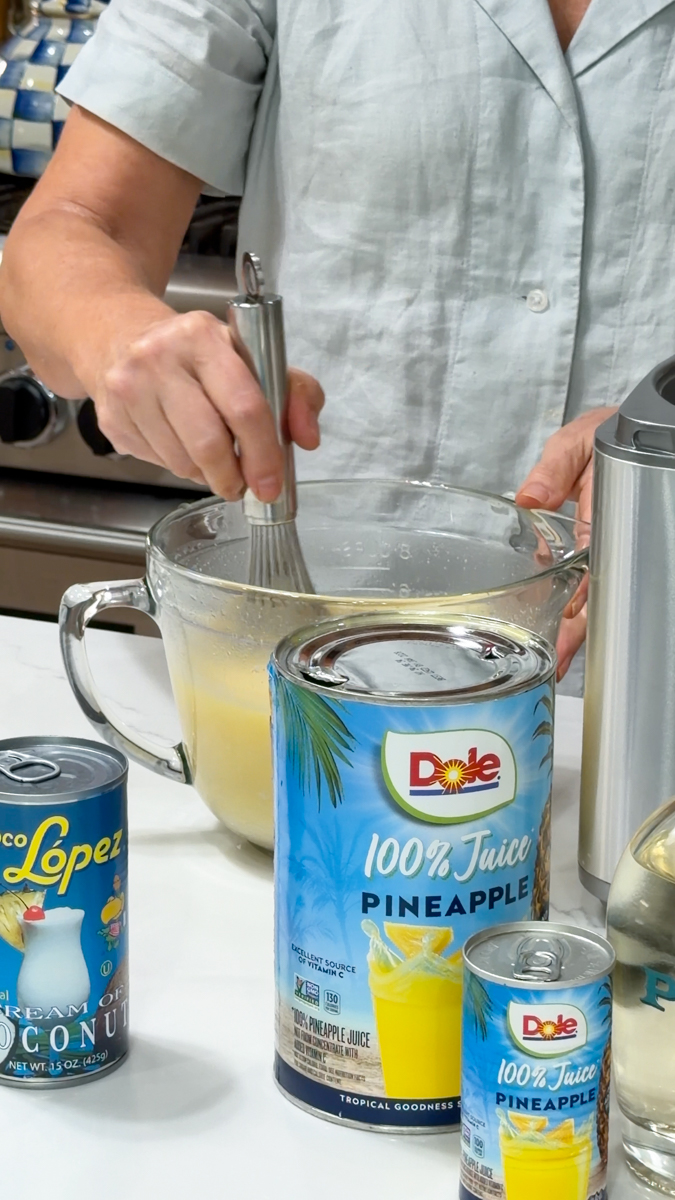 Whisking pineapple juice and cream of coconut together for piña coladas.