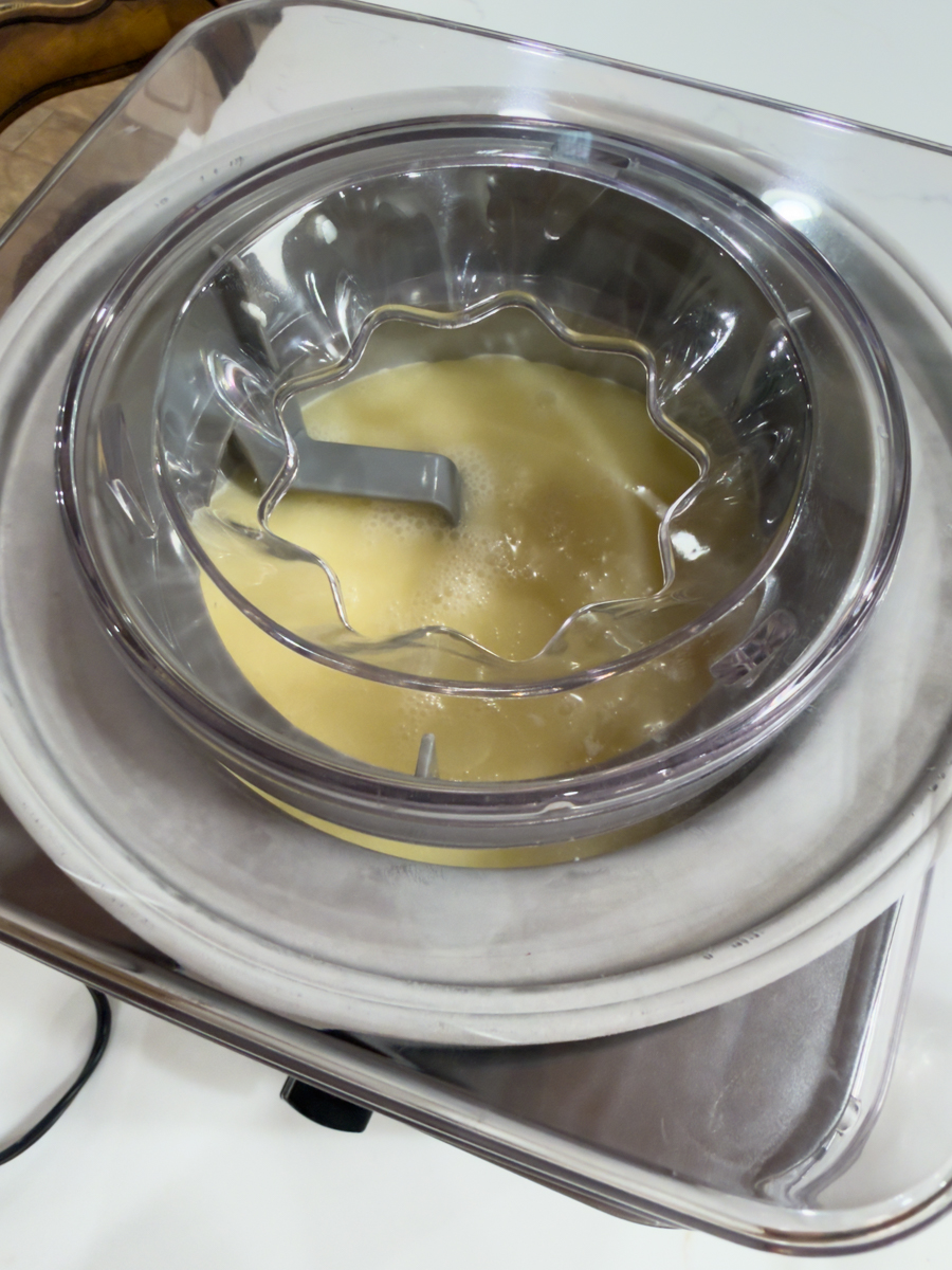 Piña colada mixture churning inside an electric ice cream maker.