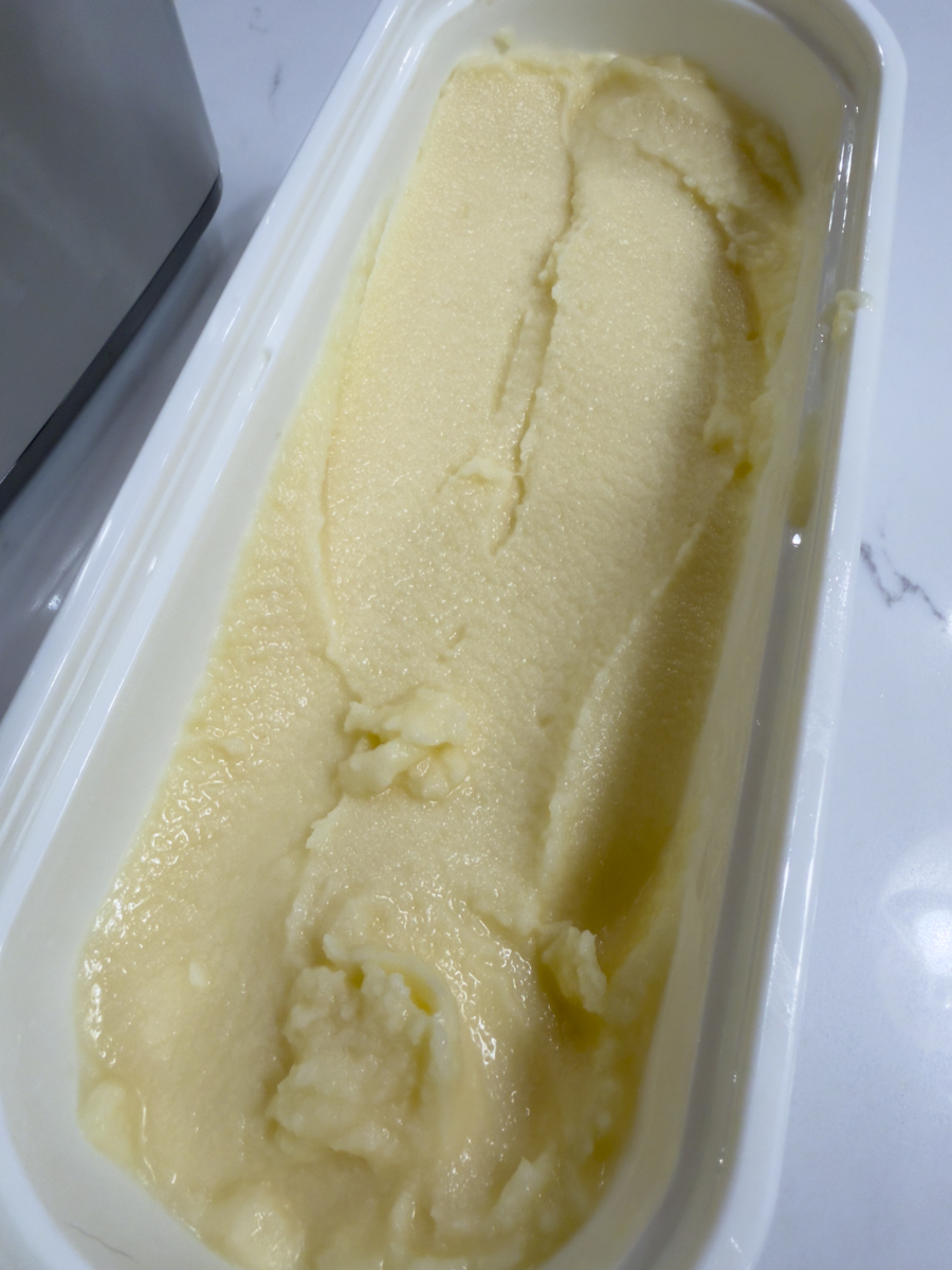 Frozen homemade piña colada base stored in a freezer container.