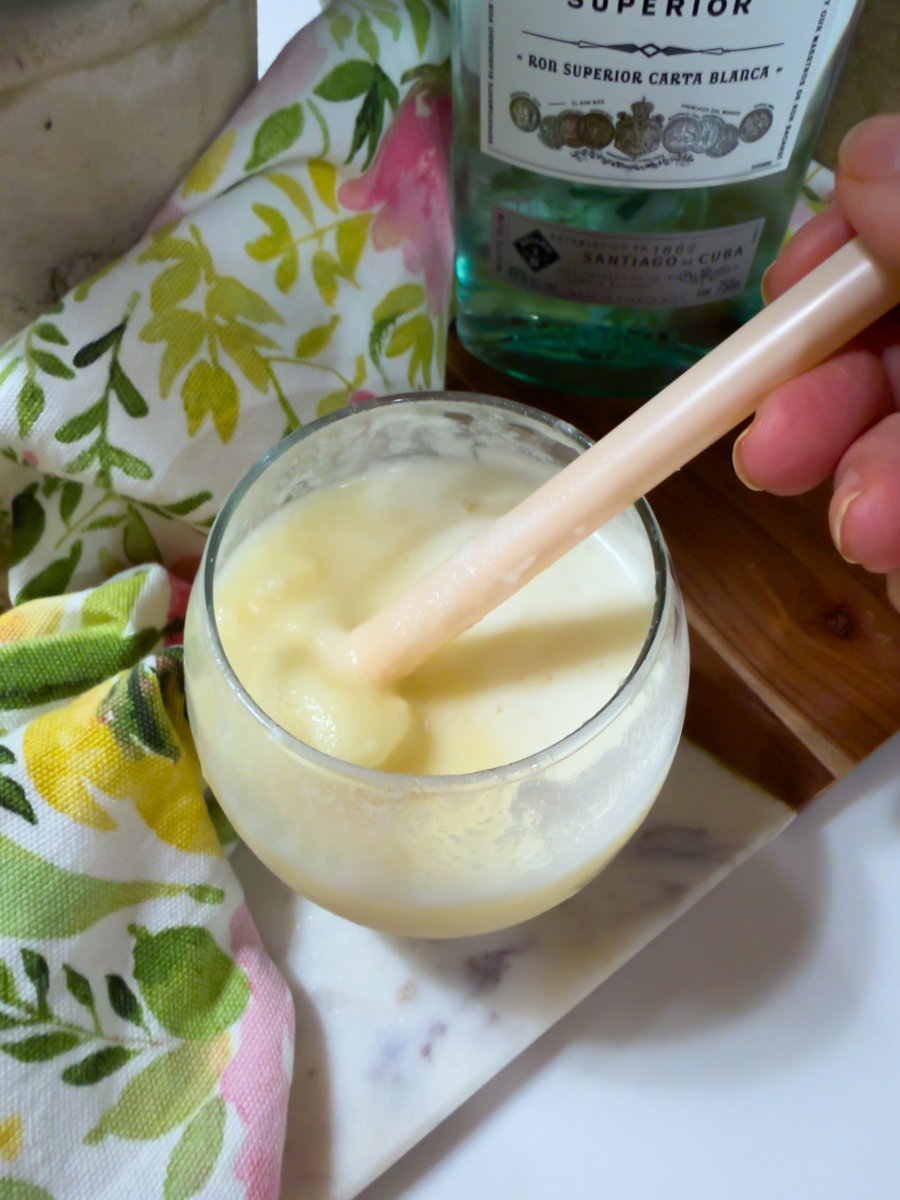 Stirring white rum into a homemade frozen piña colada.