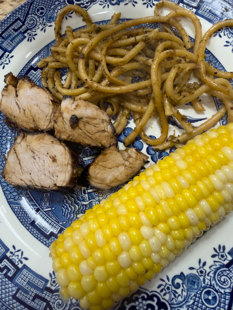 Sliced pork tenderloin served with zucchini pasta and corn on the cob