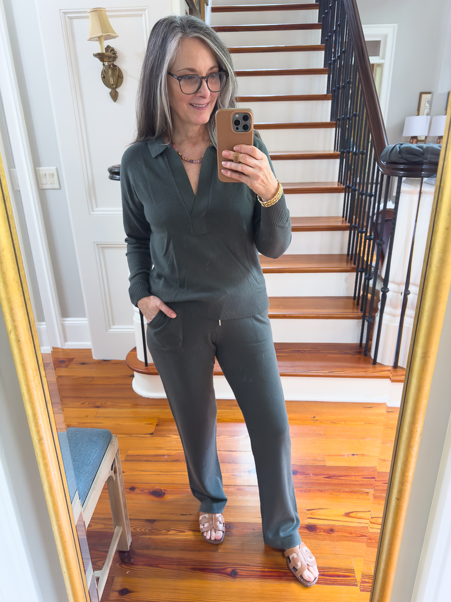 Woman wearing a moss green cashmere travel set with polo neck sweater.