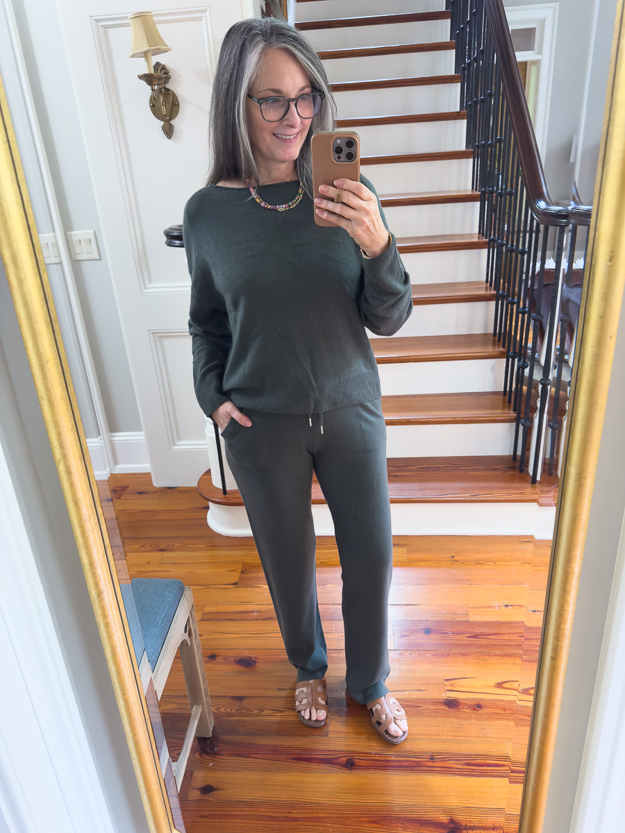 Woman wearing a moss green cashmere travel set with boatneck sweater.