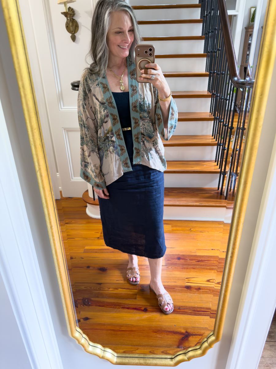 Woman wearing a navy linen tank dress with printed kimono topper and sandals