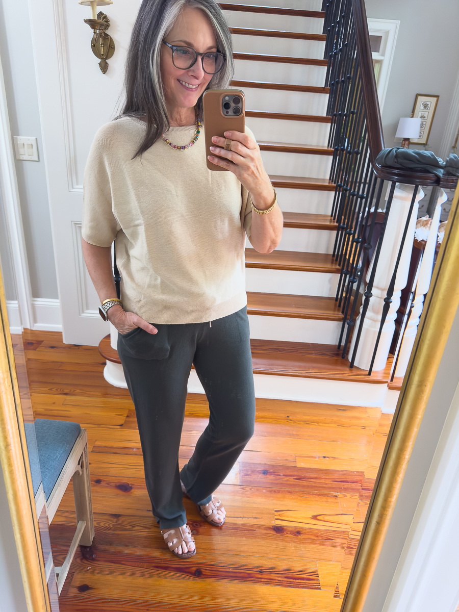 Woman wearing moss green Quince cashmere pants with oatmeal dolman sweater.