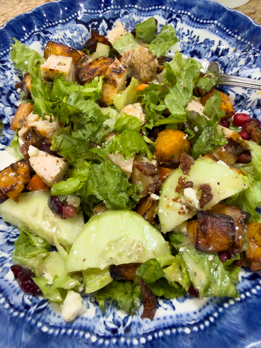 Salad with roasted butternut squash, chicken, bacon, cucumbers, and pomegranate seeds