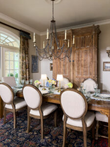 Traditional dining room with a layered summer tablescape, vintage cabinet, collected decor, and classic Southern style.