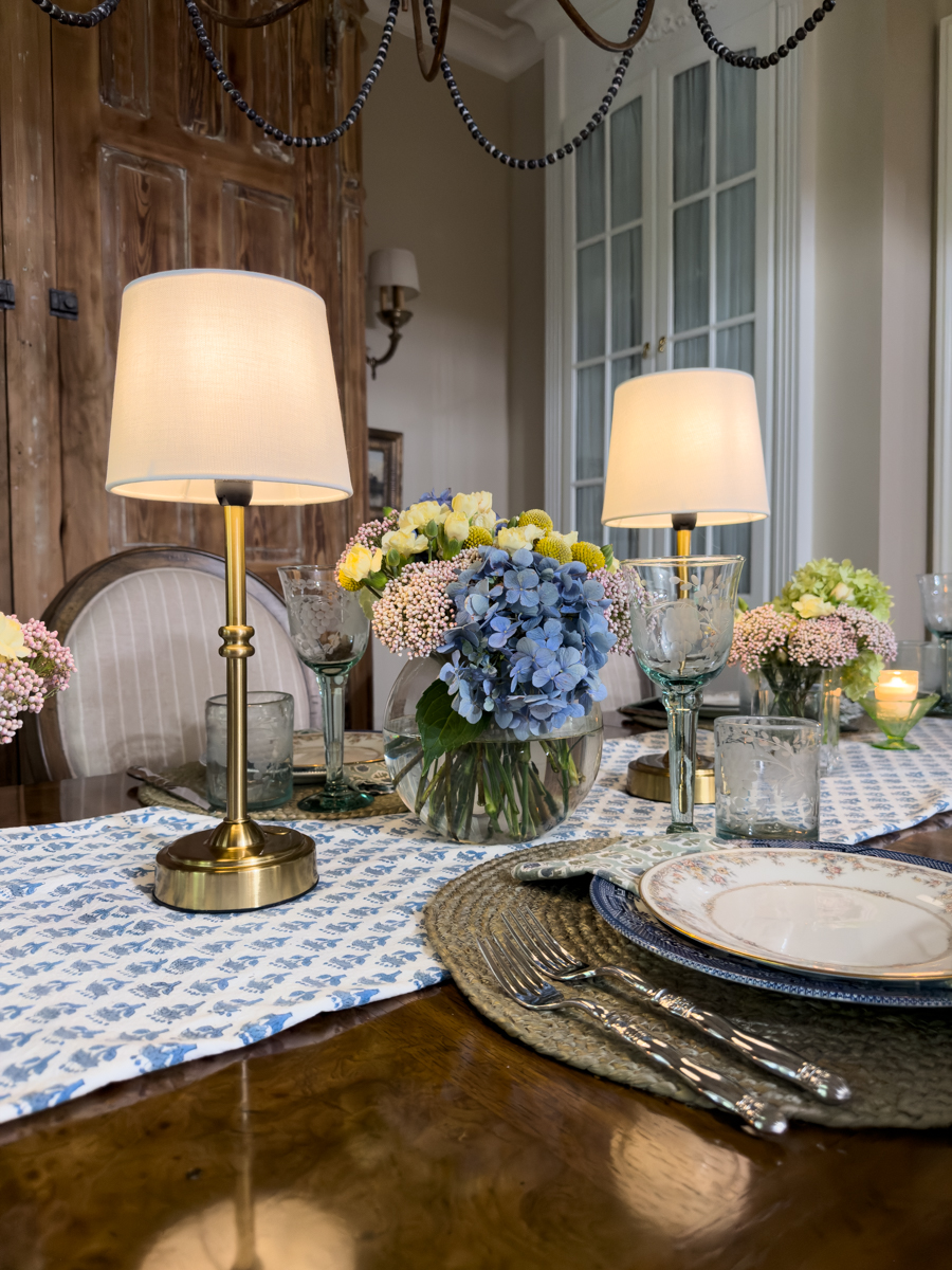 Traditional dining room with a layered summer tablescape, vintage cabinet, collected decor, and classic Southern style.