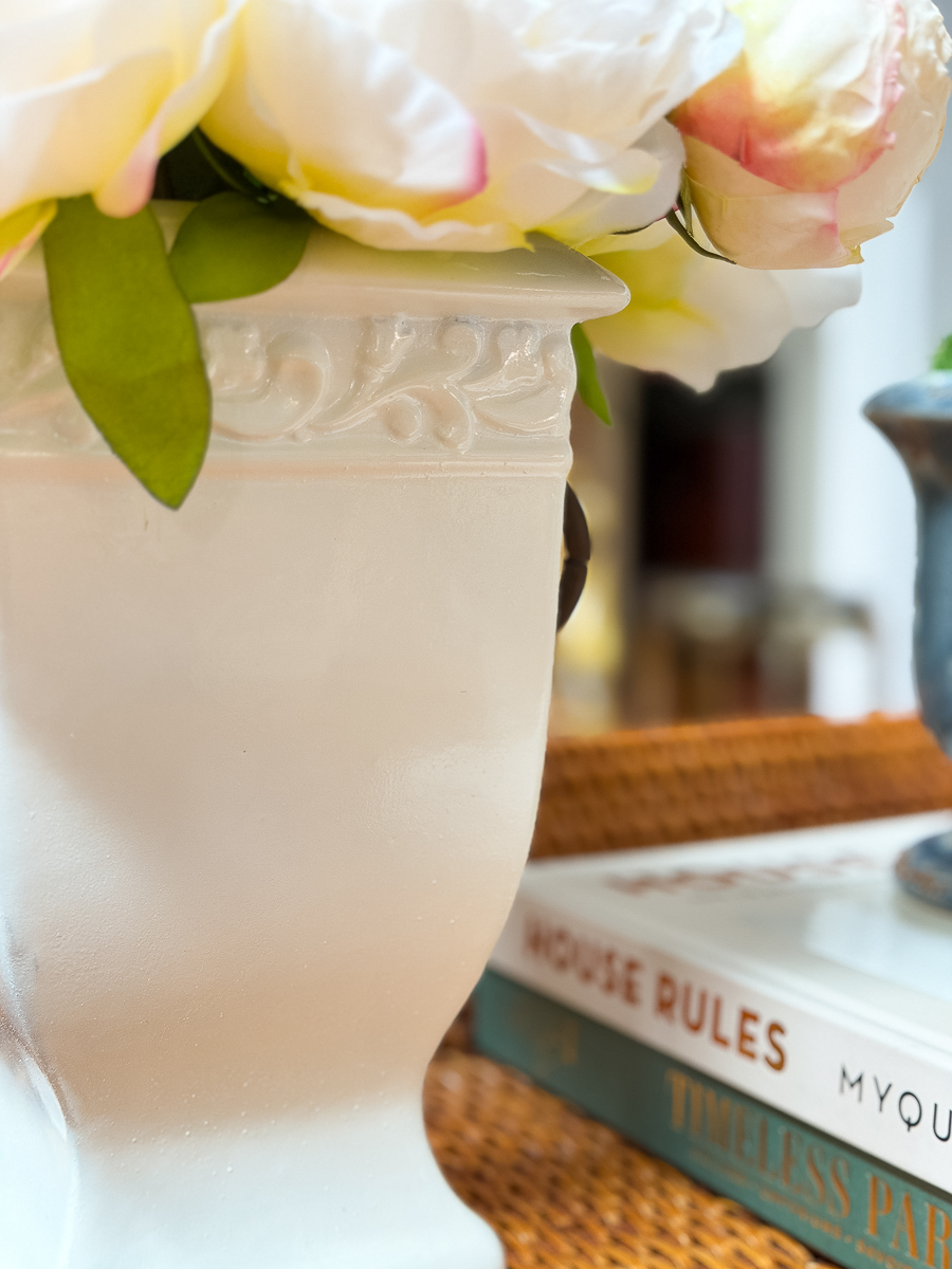 Spray painted thrifted urn filled with white flowers on a styled coffee table.