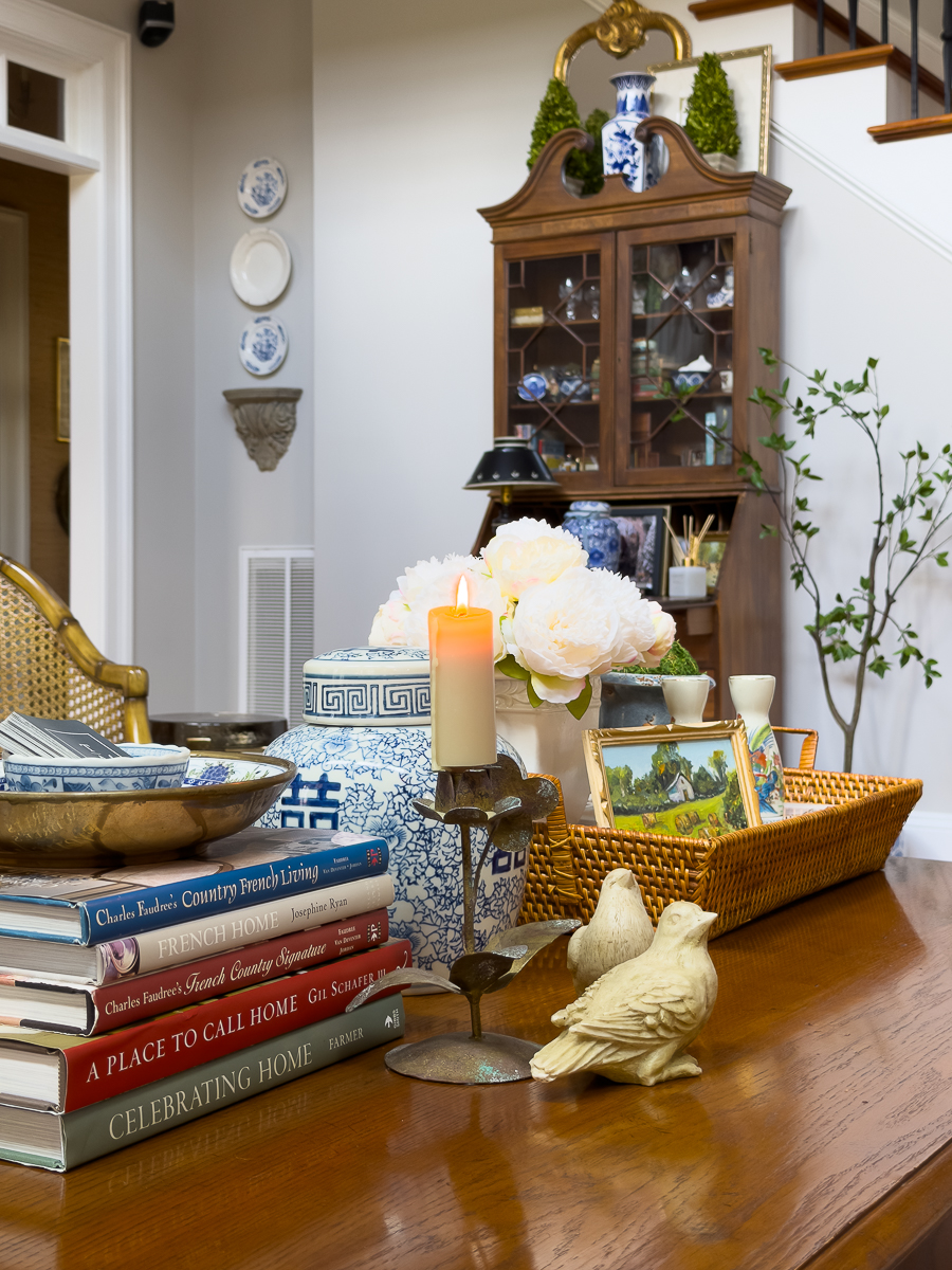 Classic wooden coffee table styled with thrifted decor including books, ginger jar, tray, flowers, and vintage accessories.