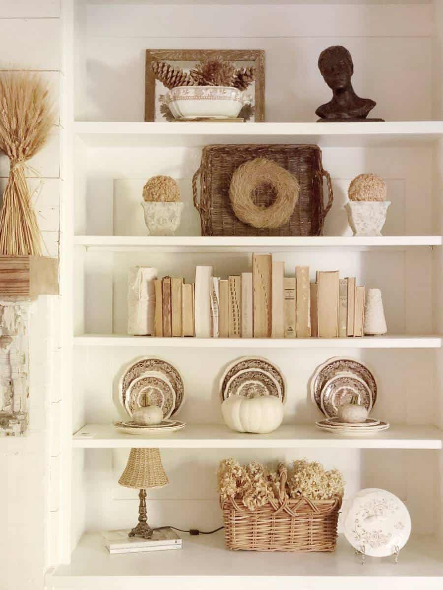 bookshelf styling with fall accents and neutral decor like books and plates. 