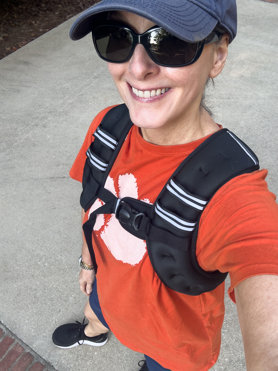 Woman wearing a weighted vest while walking outside in athletic wear.