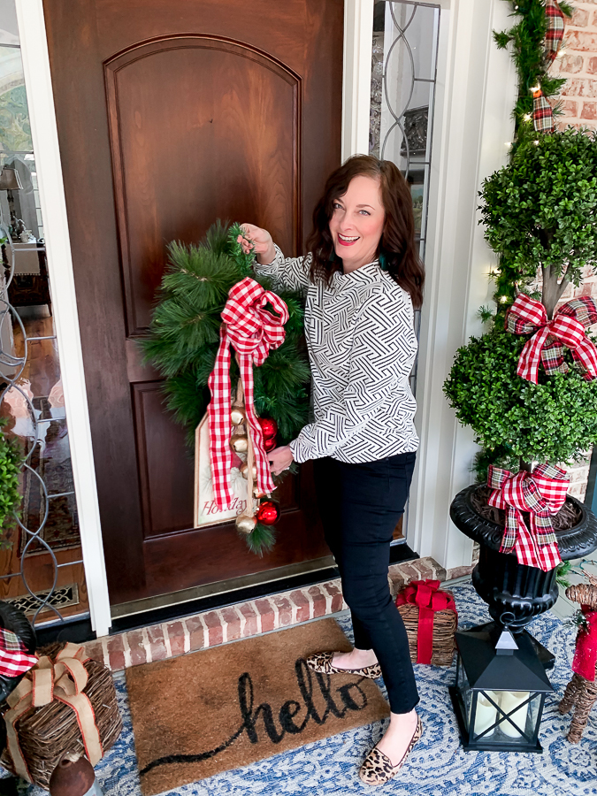 girl putting Chrismtas wreath on front door