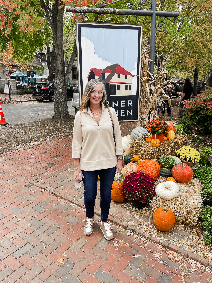 woman in jeans standing by pumpkins
