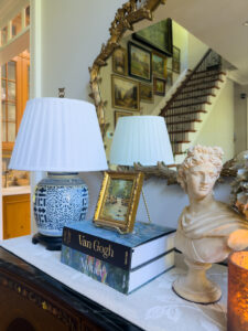 Blue and white lamp with pleated shade styled with books, bust and hydrangeas