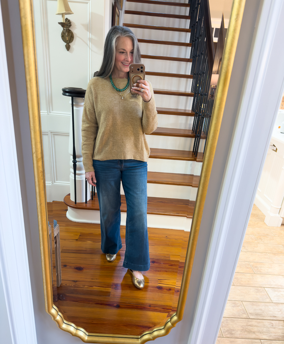 Neutral sweater styled with green beaded necklace and jeans mirror selfie