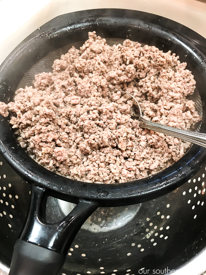 cooked ground beef being strained for fat