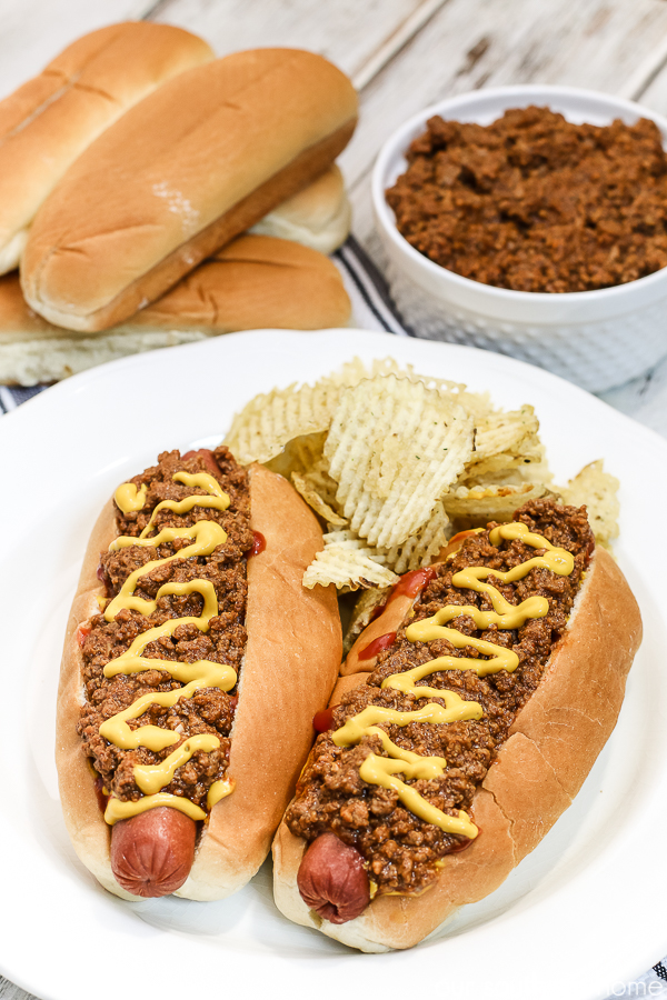 hot dogs with chili with chips on a white plate