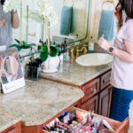 woman putting on lip gloss in mirror