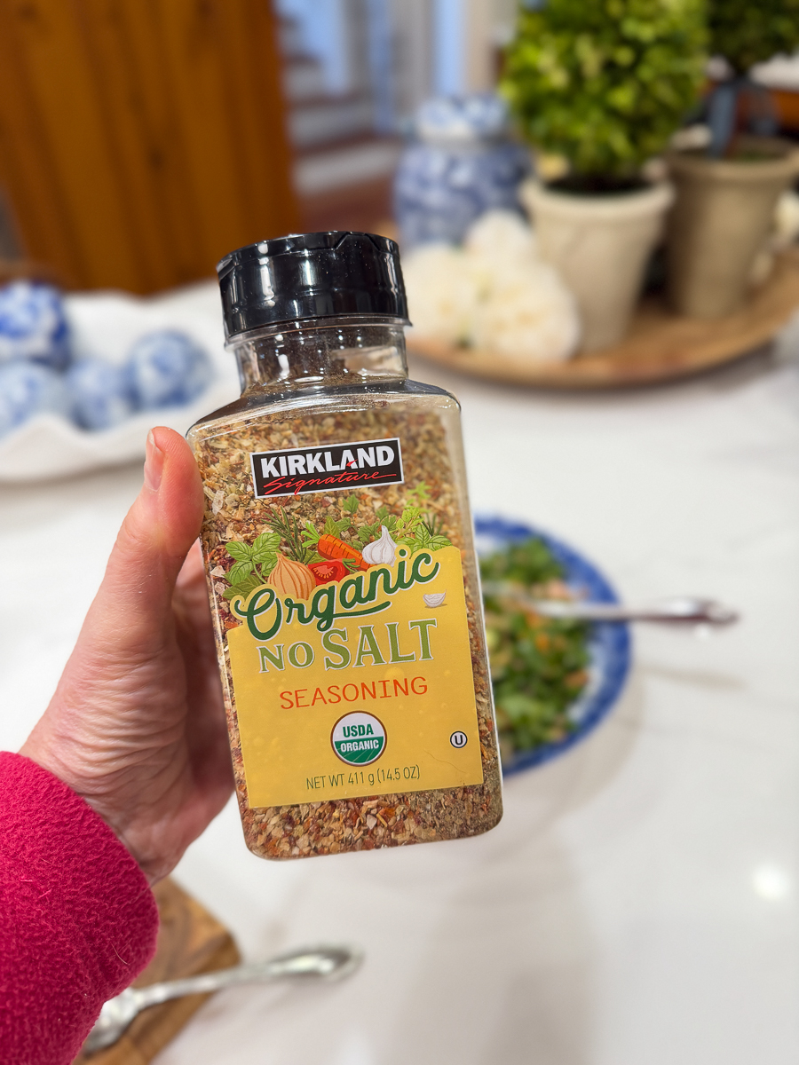Hand holding a bottle of no-salt seasoning in a home kitchen