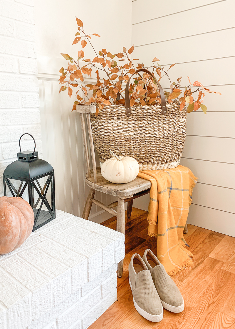 fall vignette with orange blanket and leaves in a basket. 