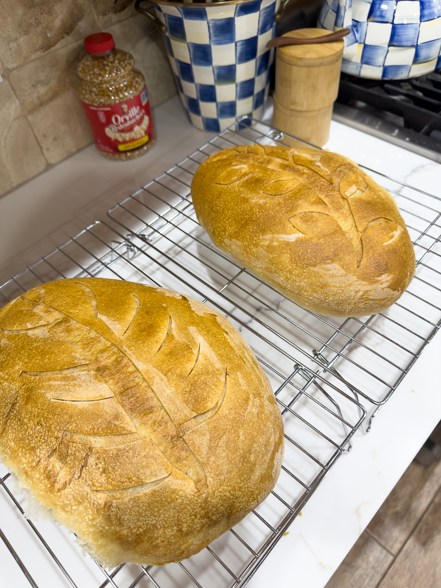 Two loaves of homemade sourdough bread cooling on a rack