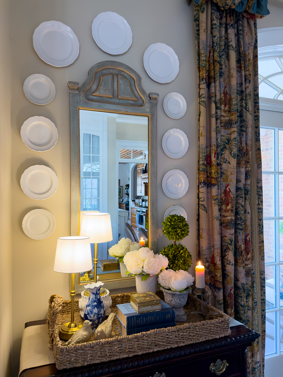 White plate wall with vintage mirror and spring vignette styled below.