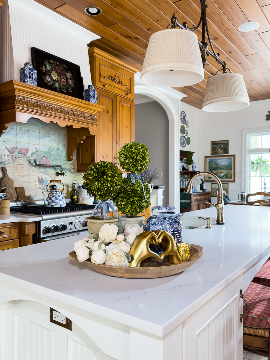 Grandmillennial Valentine’s Day decor with heart hands sculpture and boxwood topiaries.