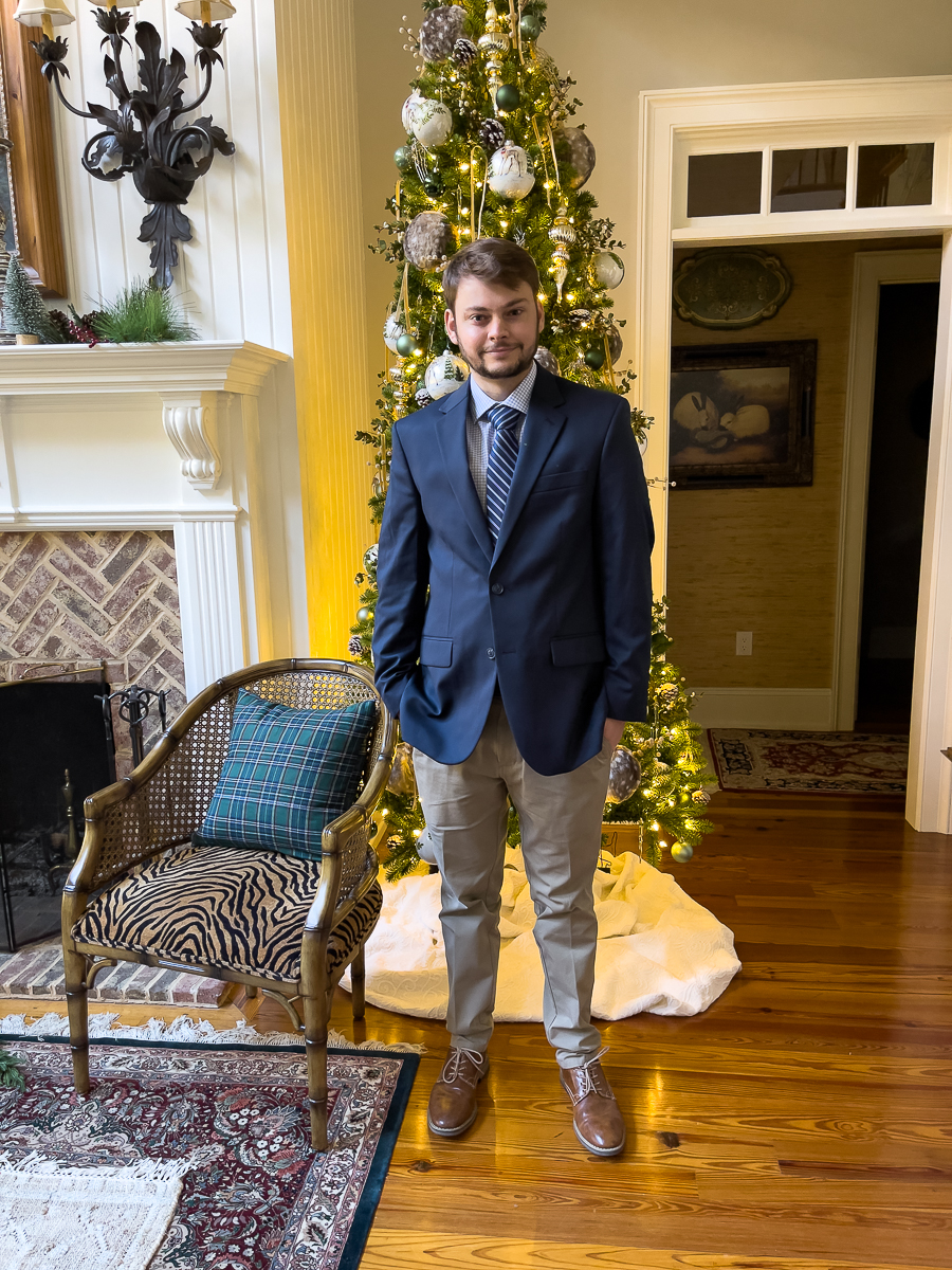 guy in a suit in front of Christmas tree